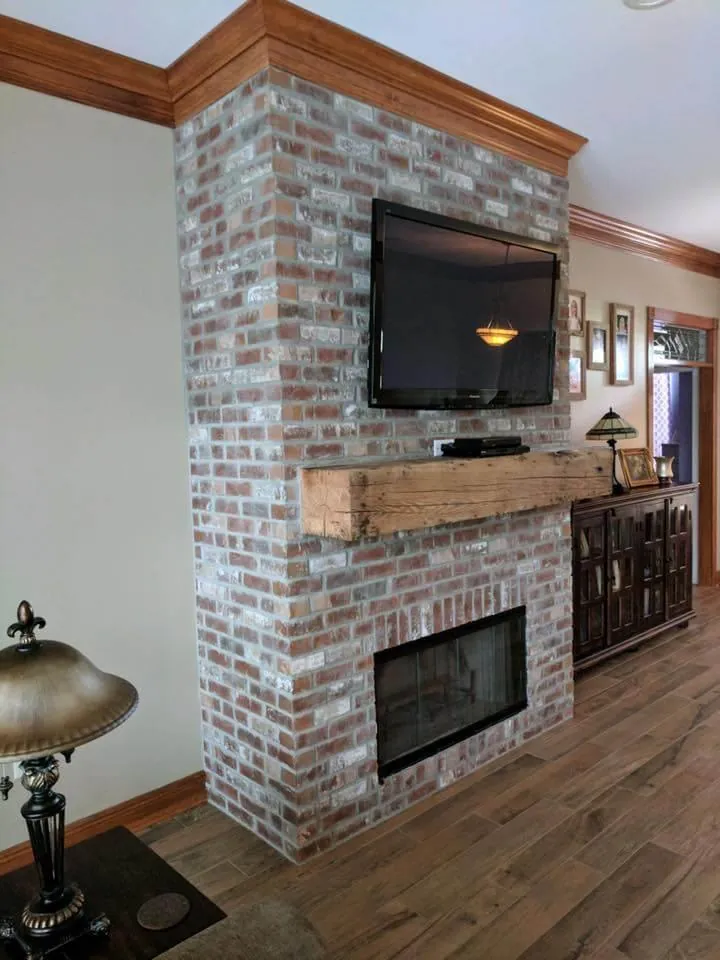 Red thin brick wall with wood mantel in a living room