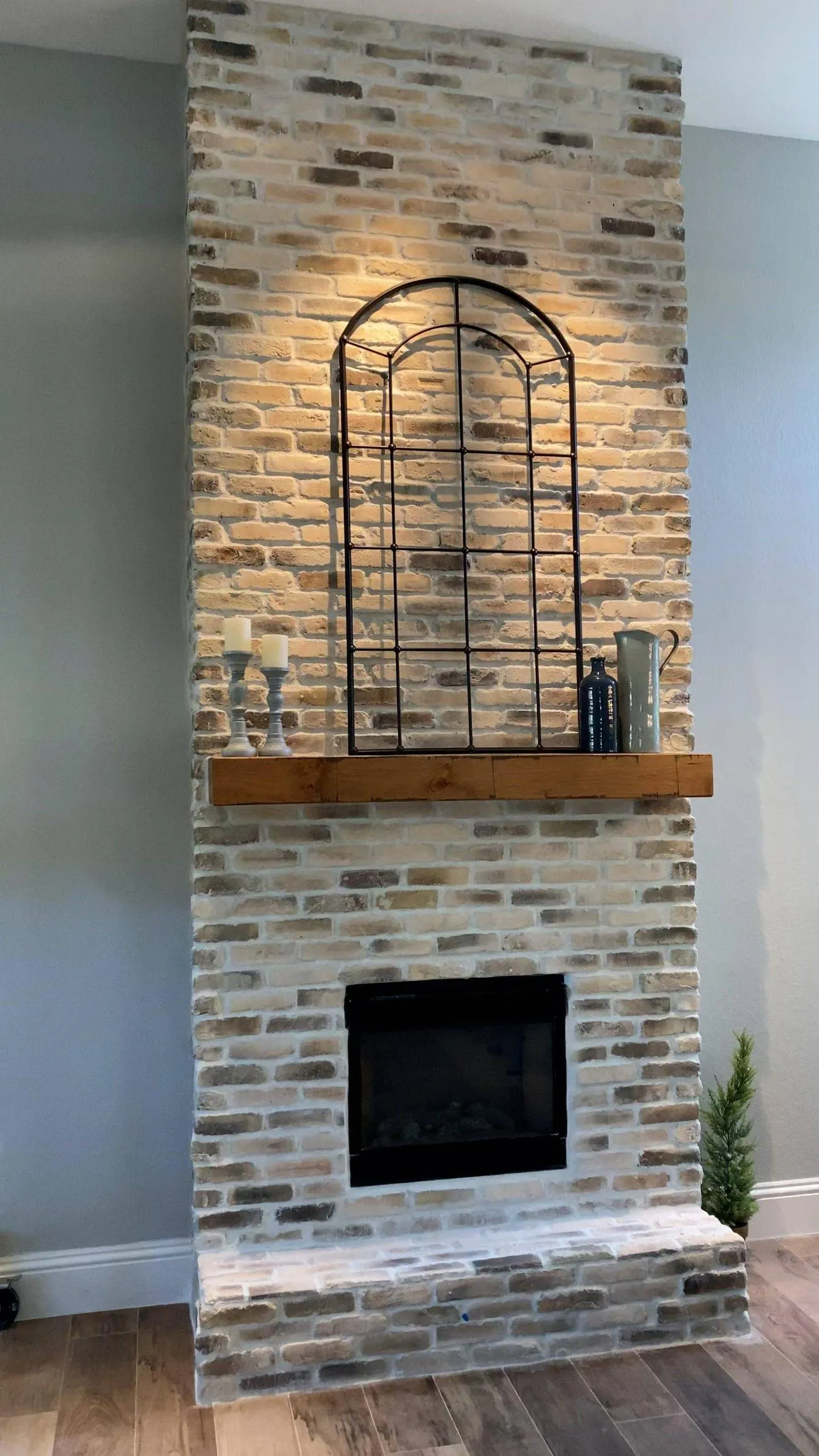 Tall thin brick veneer wall with wood mantel